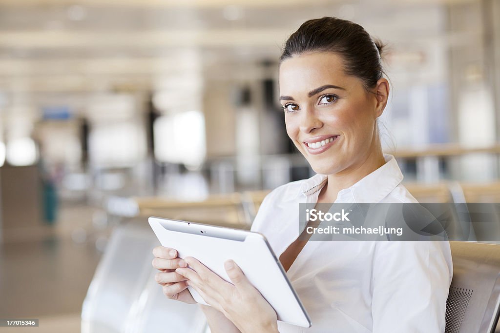 Mujer sonriente con tableta en el aeropuerto - Foto de stock de Tableta digital libre de derechos