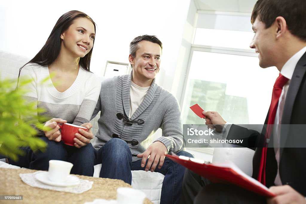 Before making agreement Portrait of modern couple looking at real estate agent giving his visiting card Adult Stock Photo