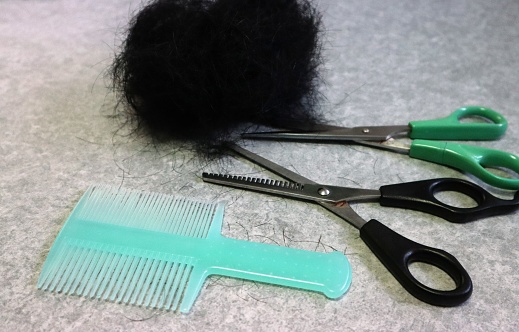 Close-up photo of hair clumps, scissors and comb