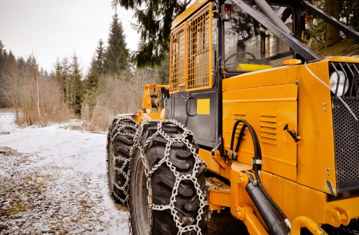Winter scenery. Logging machine giant wheels equipped with snow chains.  HDR photo.