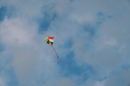 Colorful kite soars in the cloudy sky. High quality photo