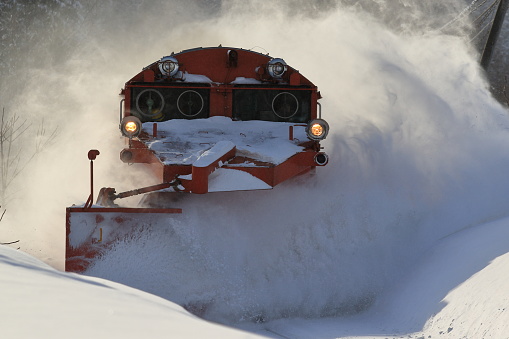 A DE15 snowplow locomotive runs by kicking away high piles of snow.