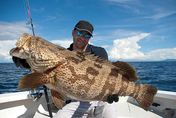 Happy  fisherman holding a grouper