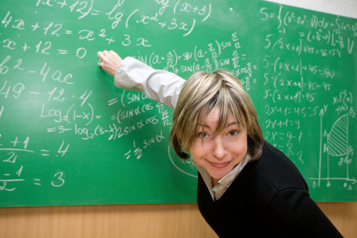 Young teacher writing numbers on the chalkboard, isolated on white background, conceptual image of education
