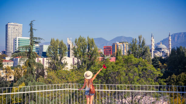 Woman holding albanian flag enjoying panoramic view of Tirana city landscape- Albania stock photo