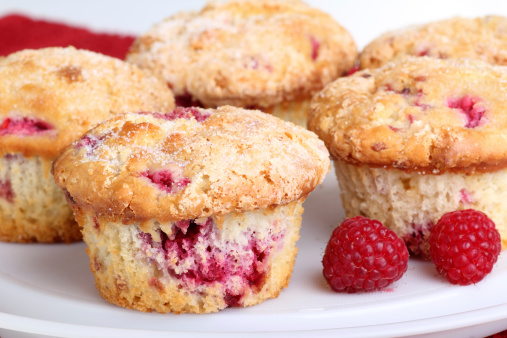 Several whole cranberry muffins and raspberry fruit on a platter