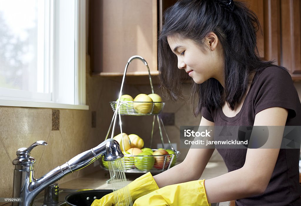 Teen girl washing dishes at kitchen sink Assistance Stock Photo