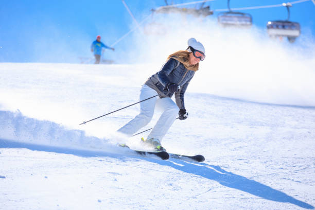 aktiver lebensstil, vitale skifahrerin beim skifahren, genießen in sonnigen skigebieten. skicarven mit hoher geschwindigkeit vor blauem himmel. - skiing point of view stock-fotos und bilder