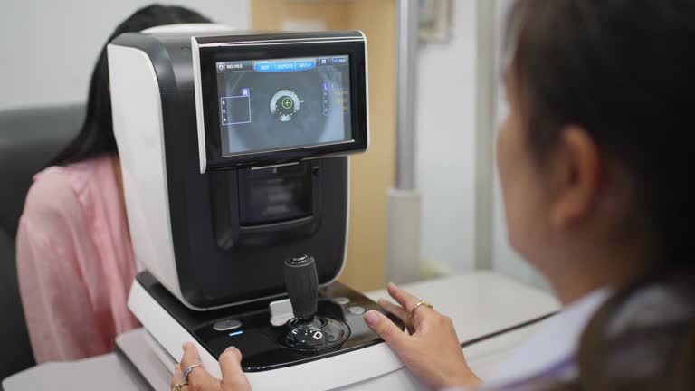 Asian woman getting her eye checked by a female optometrist