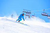 Active lifestyle, Vital senior  men snow skier skiing, enjoying on sunny ski resorts. Skiing carving at high speed against blue sky.