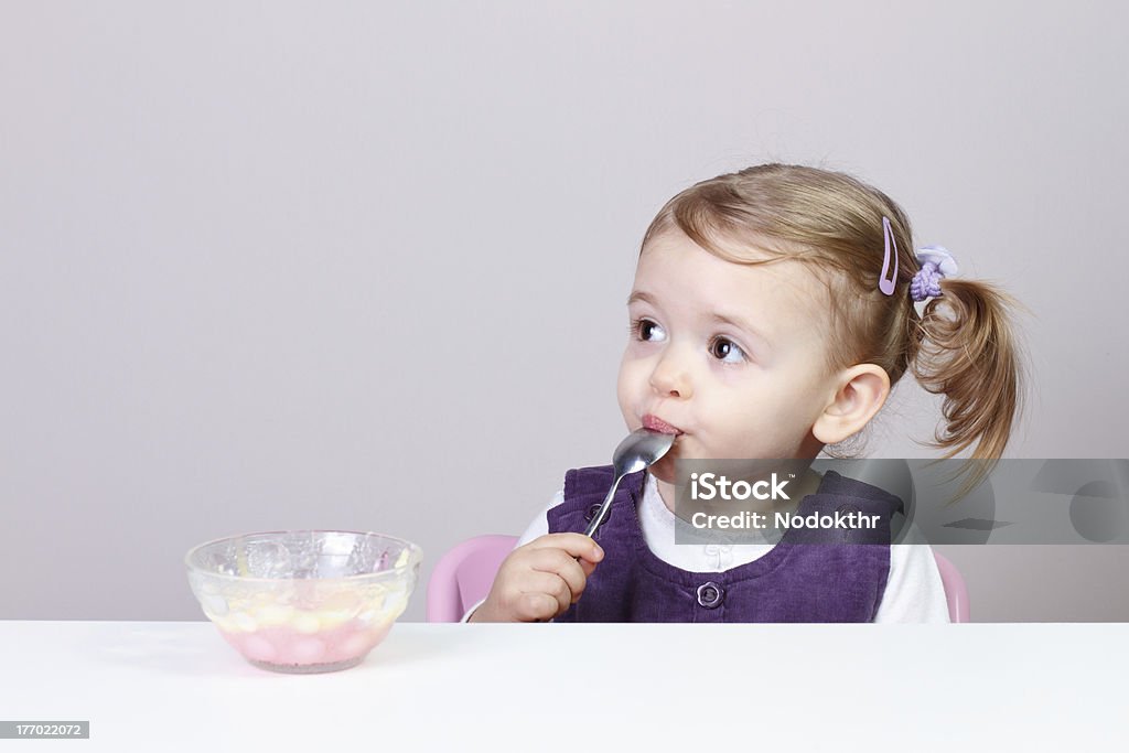 Baby Girl Having Fun While Eating 24 months old adorable little baby girl having fun while eating creamy pudding with spoon. Babies Only Stock Photo