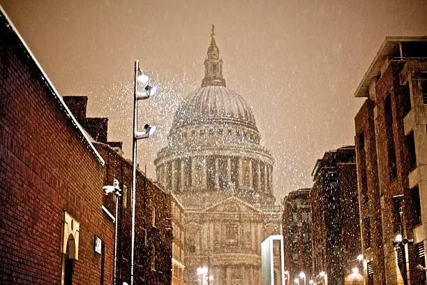 "St.Paul's Cathedral with snow. lit by streetlights, in the foreground."