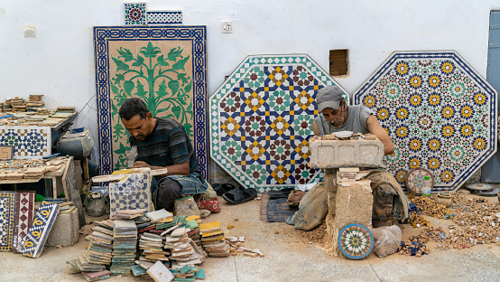 Fes, Morocco - 10 September 2022: Moroccan craftsmen working with ceramics in a craft workshop to create pots, later to be displayed outside shops in the souks, or traditional markets.