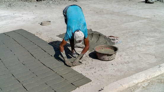 Fes, Morocco - 10 September 2022: Moroccan craftsman making tiles with cement. He fills the mold with a mixture of cement, sand, and pigment.