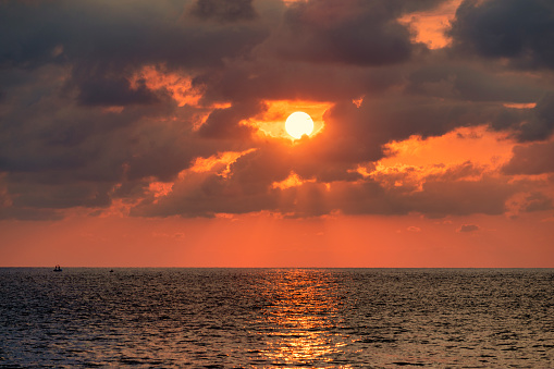 Sun behind clouds over sea