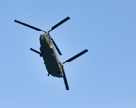 A twin rotor Chinook helicopter based at RAF Odiham flies low over East Wittering beach in East Sussex, UK