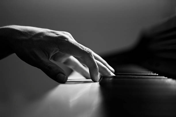 Male Hand on Piano "A black and white image of an adult male hand rested on a piano.  The image is sharp and detailed, with a very shallow depth of field." pianist stock pictures, royalty-free photos & images