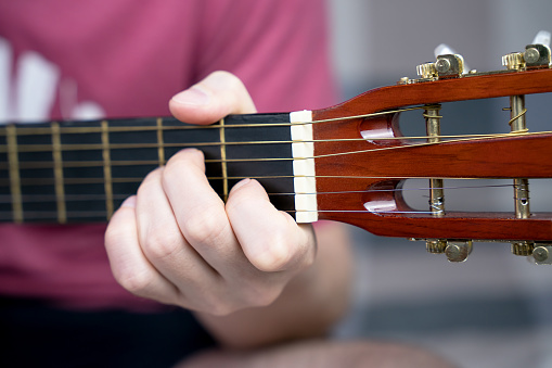 A young man plays the guitar. Close-up. Selective focus.