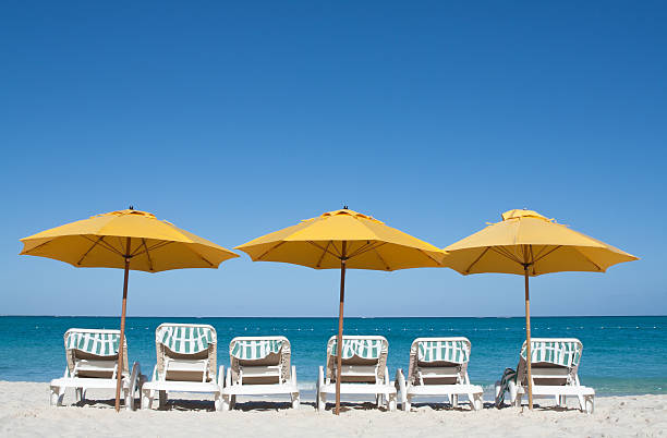 des chaises longues et des parasols sur la mer des caraïbes de la plage de sable blanc - providenciales photos et images de collection