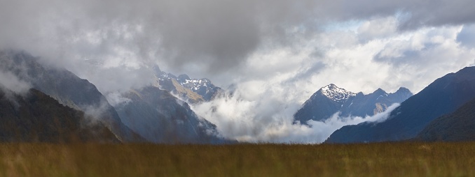 A scenic landscape of rocky mountains covered in a blanket of fluffy clouds. New Zealand