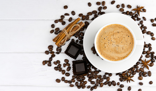 Cup of coffee, chocolate candies and coffee beans on a white background. Close-up. Top view. Copy space. Selective focus.