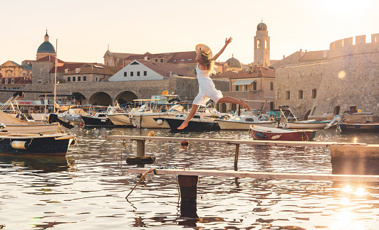 tour tourism, travel destination, vacation relax in Dubrovnik city- Woman in white dress dancing or jumping- Croatia