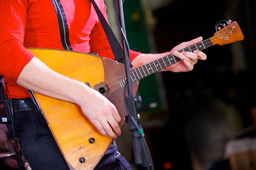 A balalaika stringed musical instrument in the hands of a male musician. The concept of culture and art.