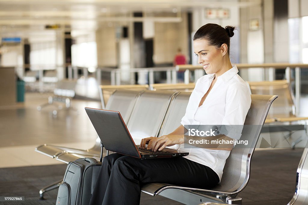 Mujer usando computadora portátil en el aeropuerto - Foto de stock de 20 a 29 años libre de derechos