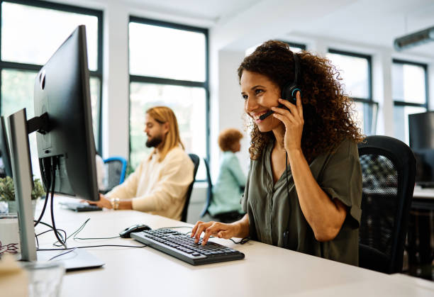 Woman working with computer in a coworking call center Side view of a woman working with computer in a coworking call center call-center stock pictures, royalty-free photos & images