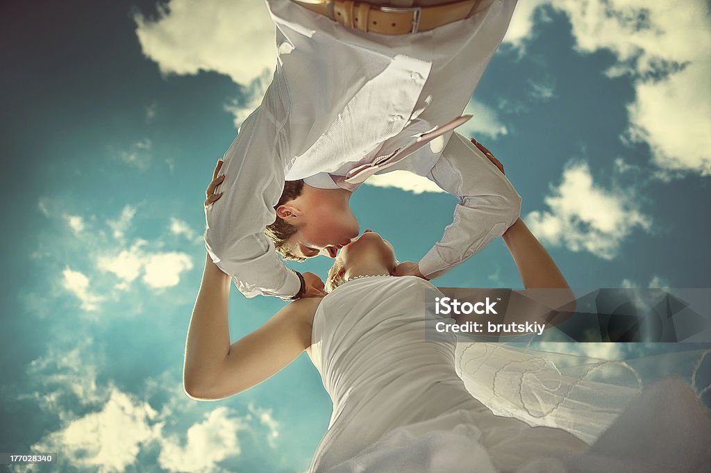 bride and groom kissing Amazing wedding couple kissing against the backdrop of the beautiful blue sky. Adult Stock Photo