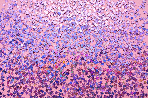 Purple sparkles in the shape of stars on a pink background.