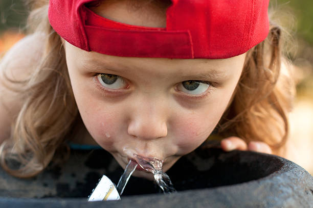 thirsty little girl drinking from water fountain