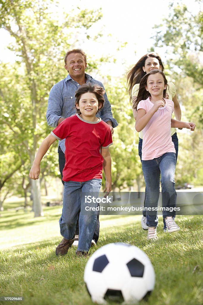 Family playing football in park Family playing football in park running towards the camera American Football - Ball Stock Photo