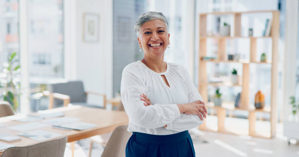 Portrait, happy and mature woman in modern office with confidence, pride and senior startup business entrepreneur. Smile on face, arms crossed and businesswoman at consulting agency in management job Senior, ceo or face of a woman in leadership with pride, success or growth mindset in a office building. Portrait, mentor or executive manager with business experience, marketing knowledge or vision senior women stock pictures, royalty-free photos & images
