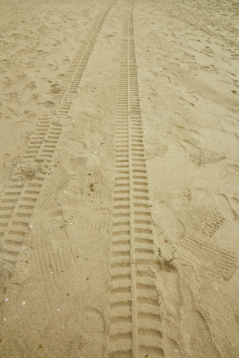 These are two tyre tracks left on a beach.