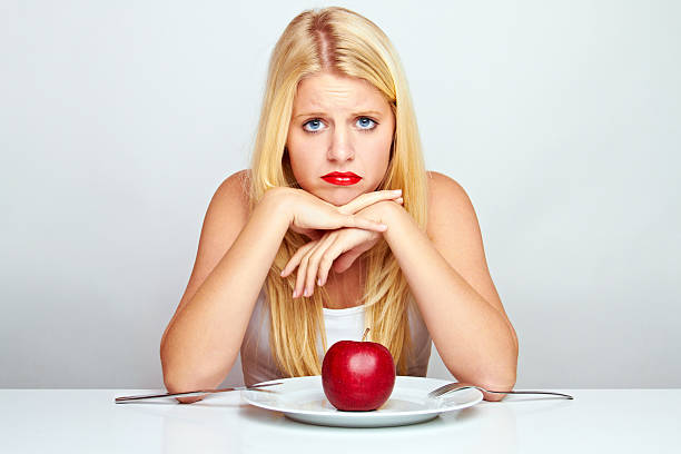 young blond woman with an apple on a plate stock photo