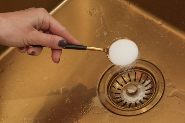 istock Cleaning kitchen sink with bakIng soda to keep sinks draining well and prevent clogs. Safe, effective, cheap, natural solution for clogged drains. 1770324420