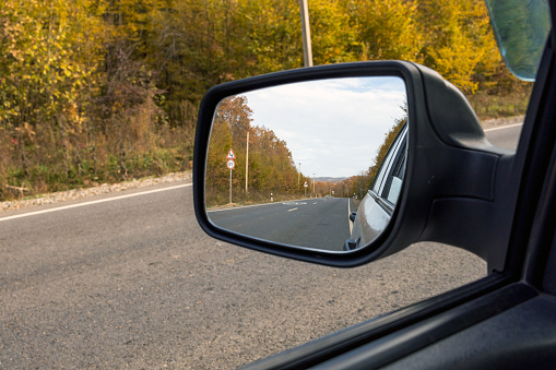 Autumn landscape in the mountains is reflected in the car mirror