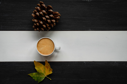 Cup of coffee and dry leave on wooden background