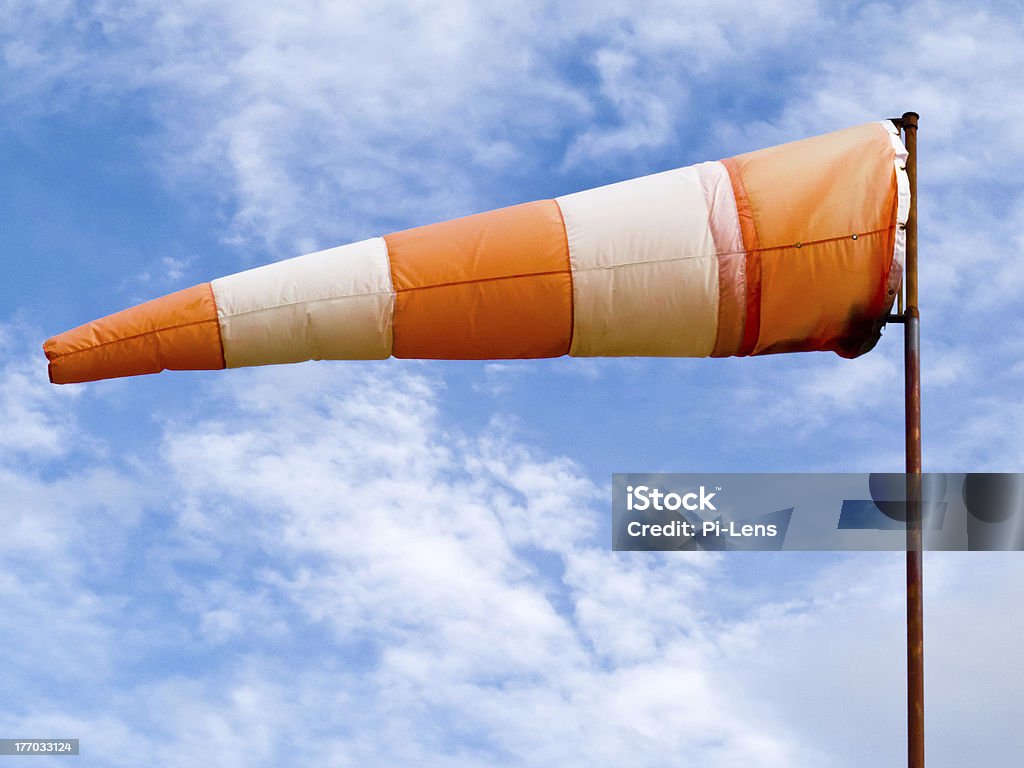 Full wind cone weather vane on windy day Red and white windsock wind filled partially clouded blue sky background Aerospace Industry Stock Photo