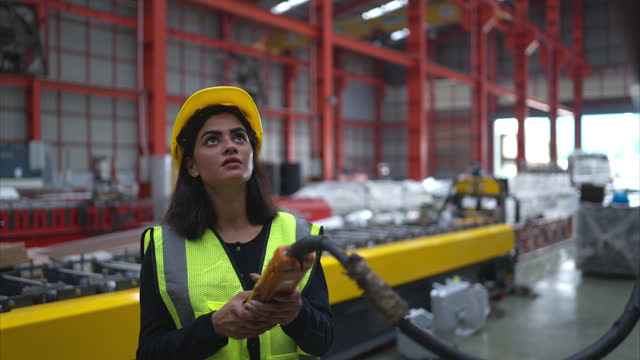 Female warehouse worker in charge of using a crane to raise rolls of metal sheets in the warehouse. to import metal sheet manufacturing belts
