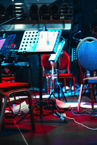 Photo of Musical music stand on stage. Scattered sheets of music on the floor