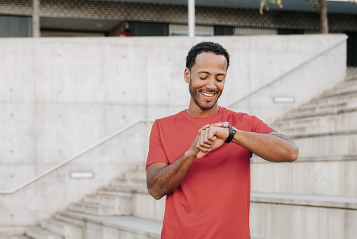 Man looking at smart watch after workout on a concrete stair in Barcelona