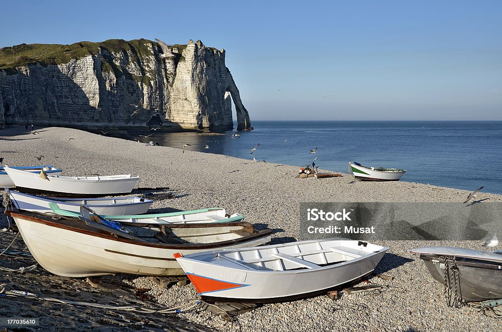 Small boats on pebble beach of Etretat in France "Small fishing boats on the famous pebble beach and cliffs of Etretat, commune in the Seine-Maritime department in the Haute-Normandie region in northwestern France" Beach Stock Photo