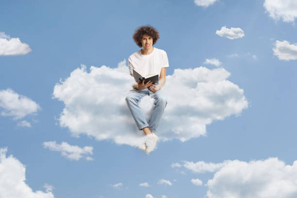istock Young man with curly hair sitting on a cloud and holding a book 1770361045
