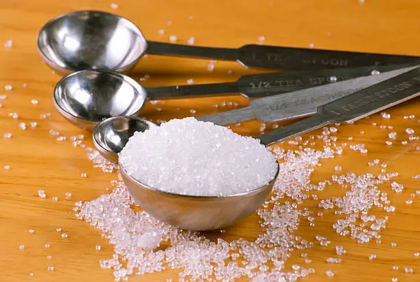 Close up of a measuring spoon filled with white sugar.You may also like: