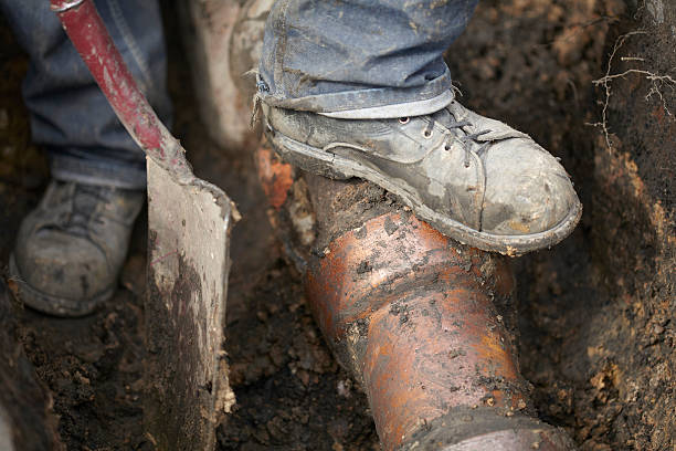 Builder Repairing Sewerage Pipe On Site Newly exposed victorian sewerage pipe and drain prior to replacement. Shot outside at close proximity. Shot show original paving bricks and dug out hole hole in pants stock pictures, royalty-free photos & images