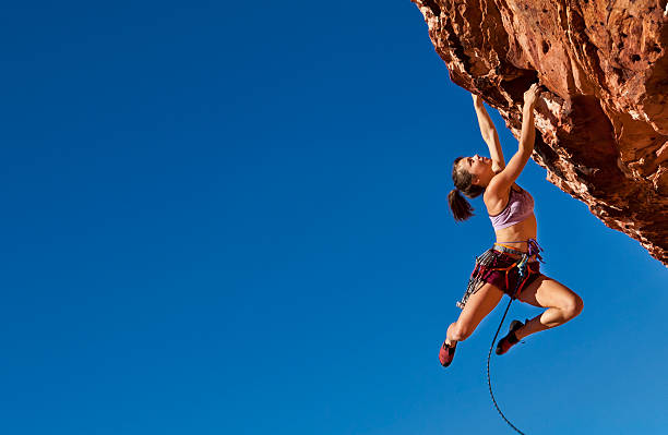 Female climber clinging to a cliff. stock photo