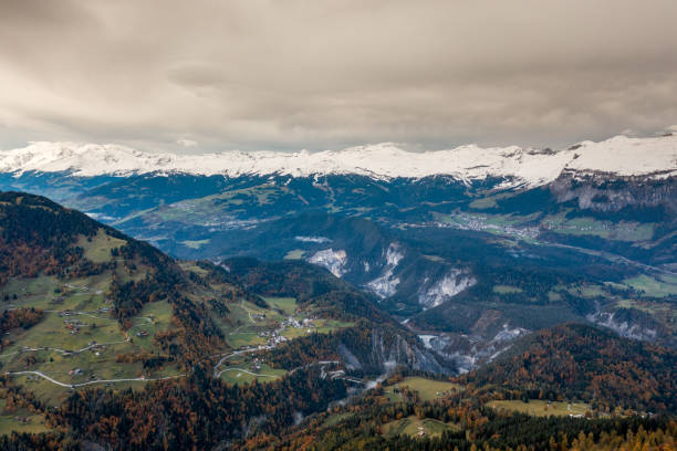 горный пейзаж в швейцарских альпах с заснеженными вершинами и цветным лесом - graubunden canton surselva panoramic scenics стоковые фото и изображения