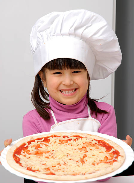 Pizza girl. Little girl holding a pizza.Little girl with a chef cap holding a pizza. girls getting ready to go out stock pictures, royalty-free photos & images